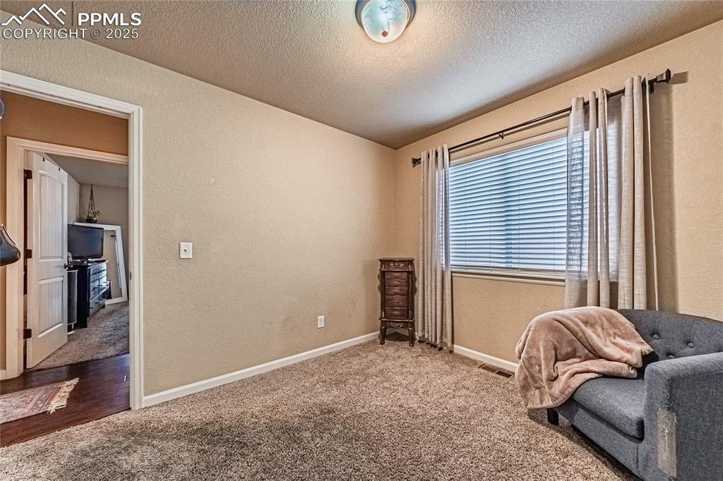 Bedroom featuring a textured wall, carpet floors, and a textured ceiling