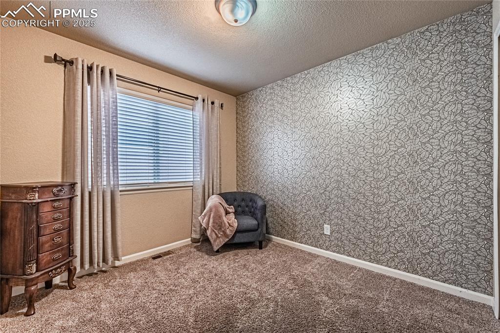 Bedroom featuring a textured ceiling, carpet floors, wallpapered walls, and a textured wall