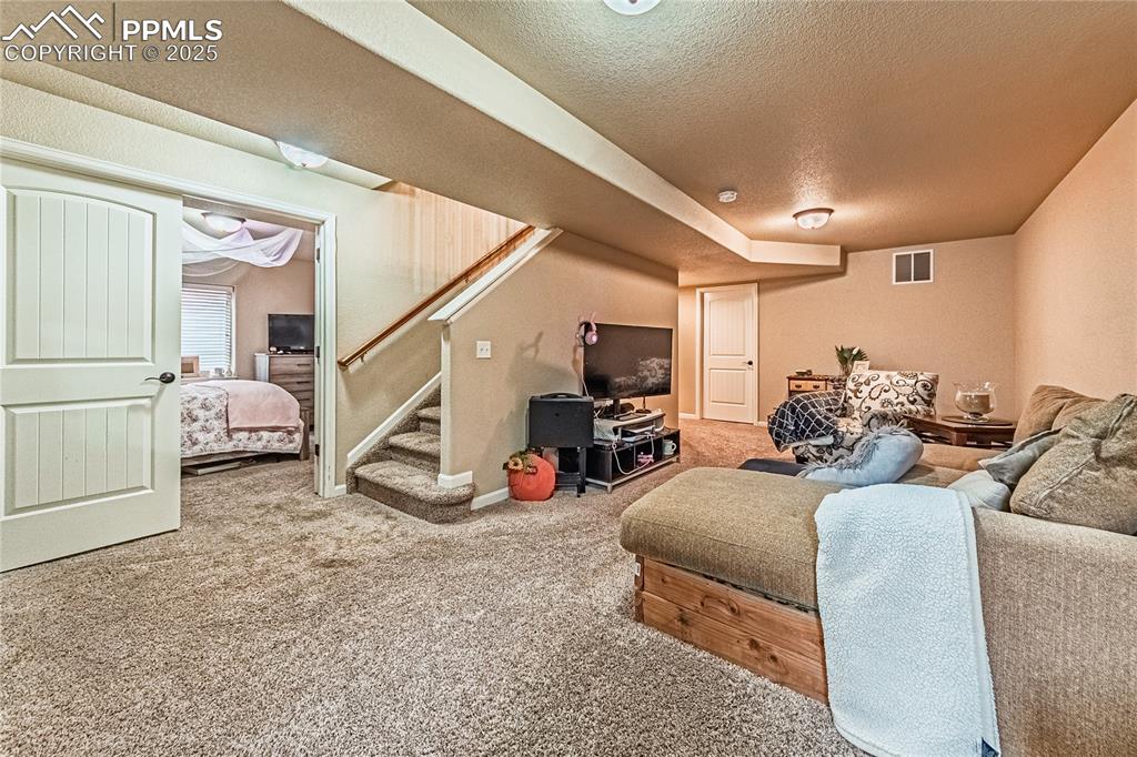 Carpeted living room featuring stairway and a textured ceiling