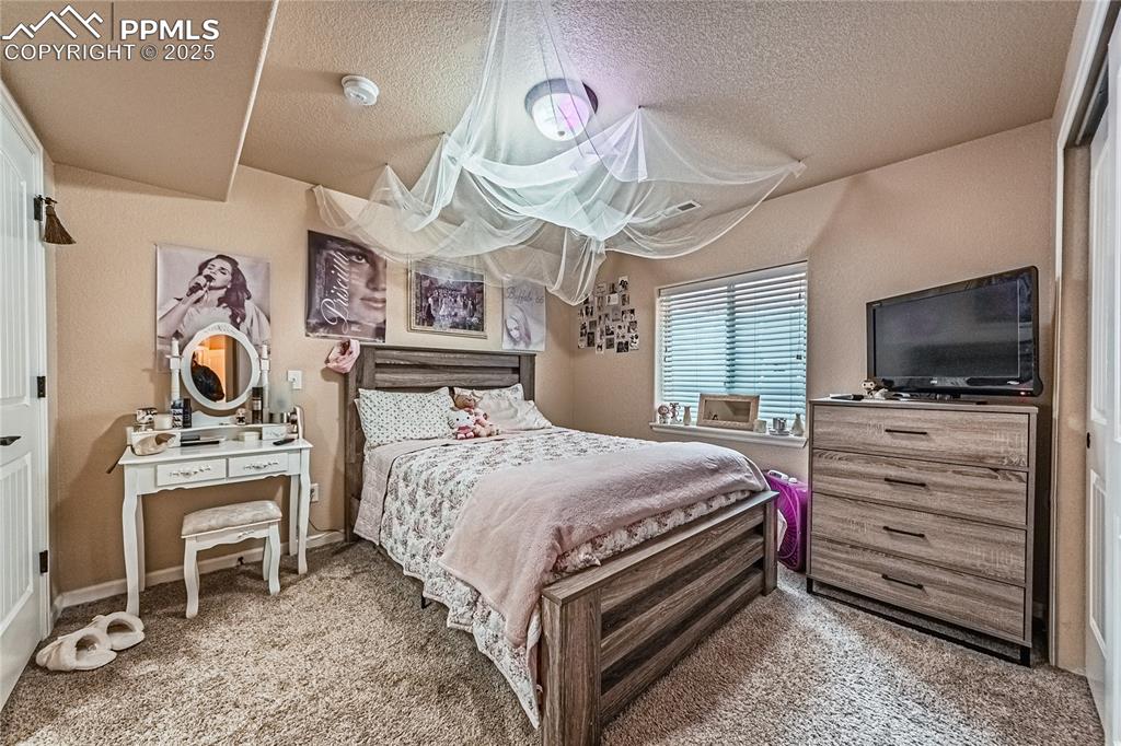 Carpeted bedroom featuring a textured ceiling and baseboards
