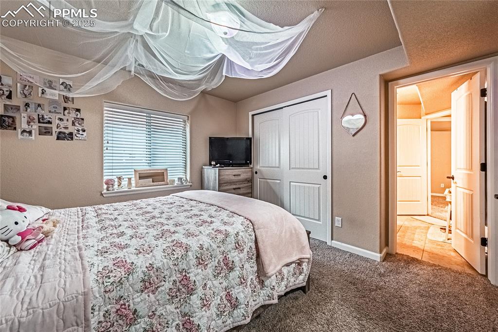 Carpeted bedroom featuring a textured wall, a closet, and tile patterned floors