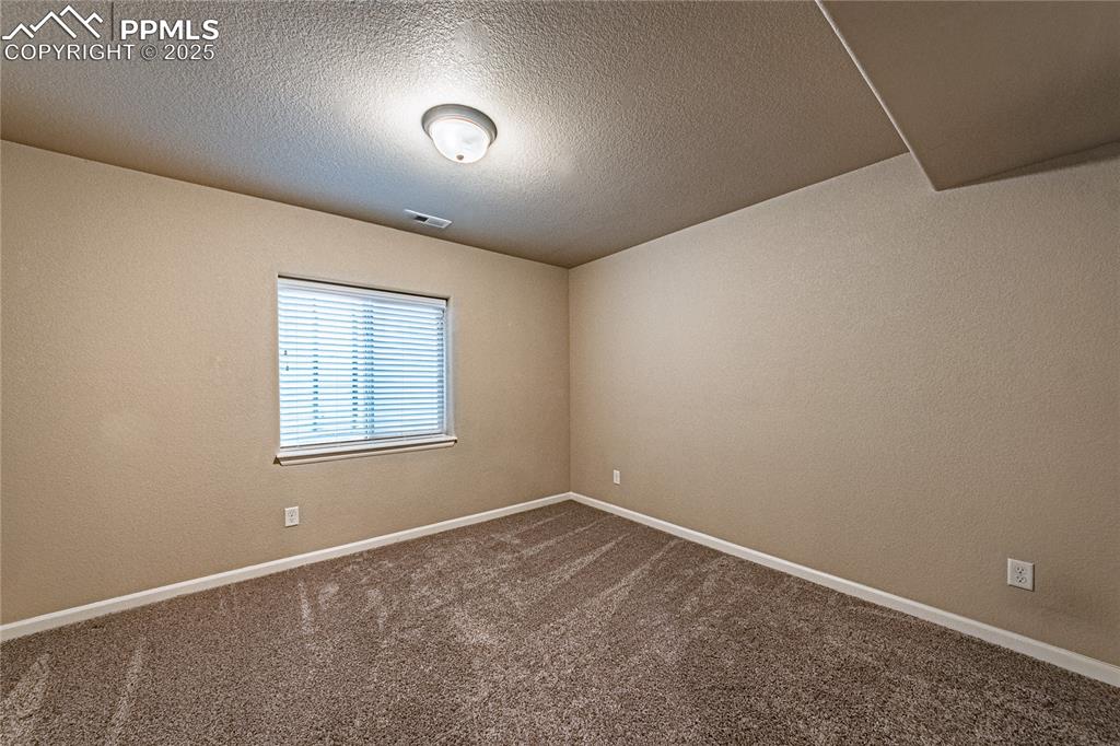 Bedroom featuring a textured wall, dark colored carpet, and a textured ceiling