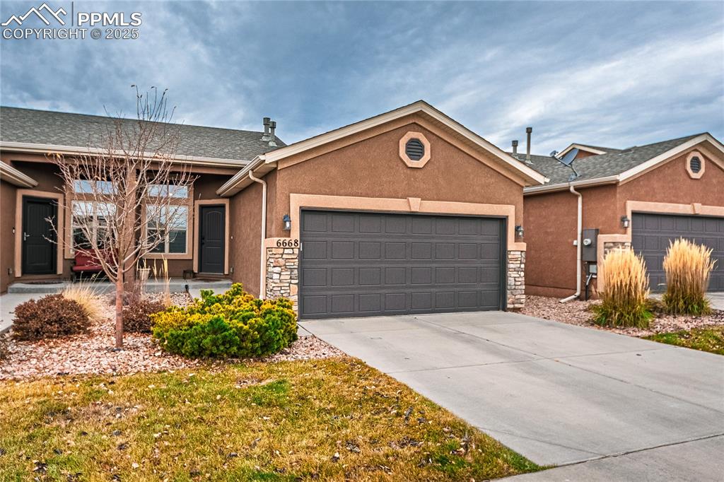Ranch-style home featuring a garage, stucco siding, driveway, and stone siding