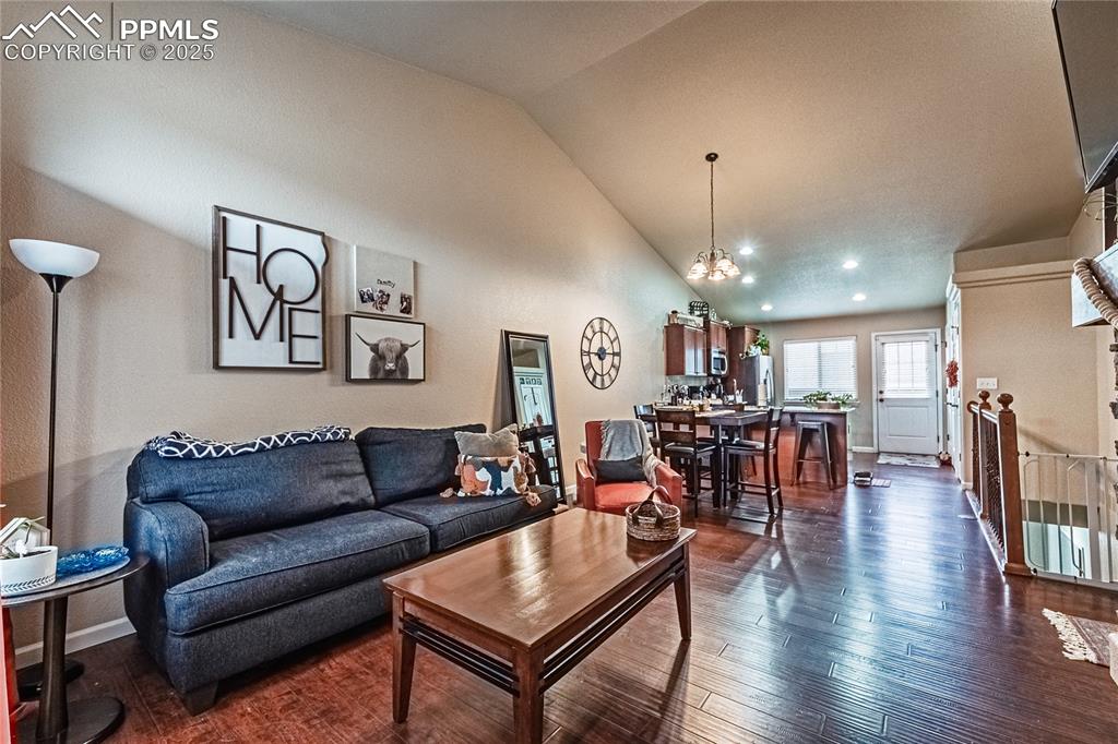 Living room with dark wood-style floors, recessed lighting, and high vaulted ceiling