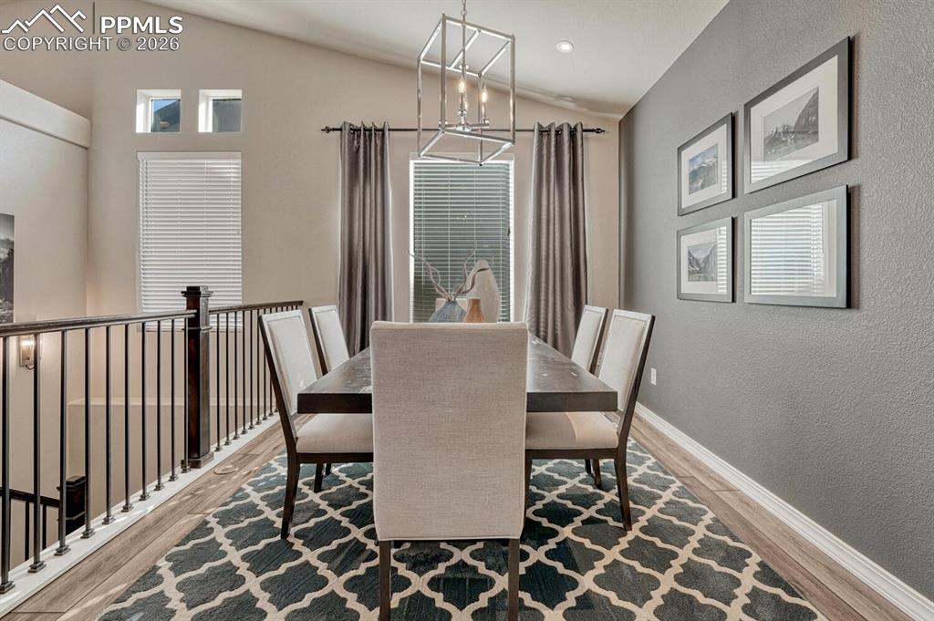 Formal Dining Room with modern light fixture, accent wall, and large view window.