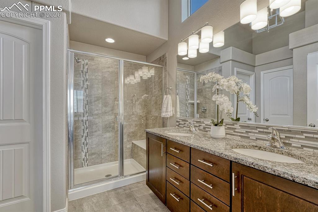 Spa-Like Shower Bathroom in the Primary Bedroom includes a dual sink comfort height vanity and enclosed tiled shower with built-in seat.