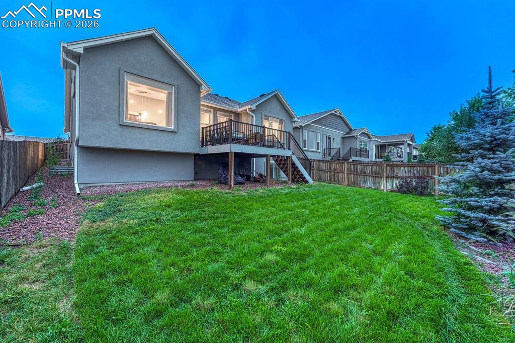 Fenced backyard with composite deck and green grass.