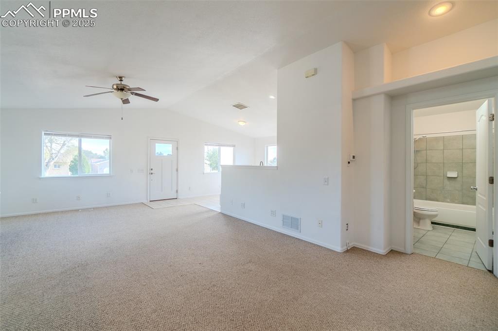 Unfurnished living room with light colored carpet, lofted ceiling, and a ceiling fan