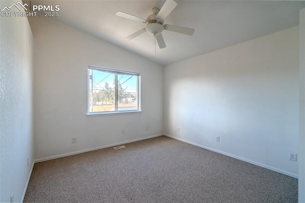 Unfurnished room with lofted ceiling, carpet floors, and a ceiling fan