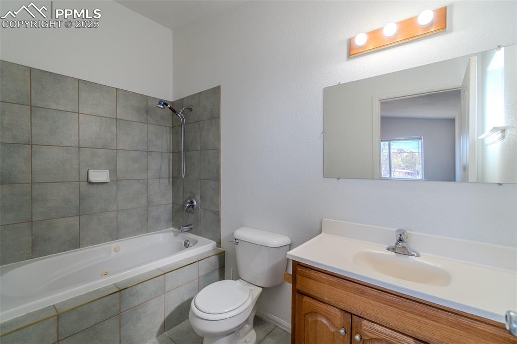 Bathroom featuring vanity, tiled shower / bath combo, and light tile patterned flooring