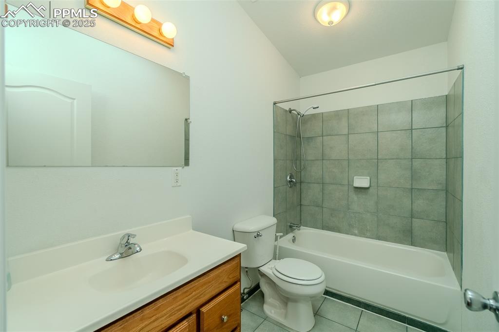 Bathroom with light tile patterned floors, tub / shower combination, and vanity