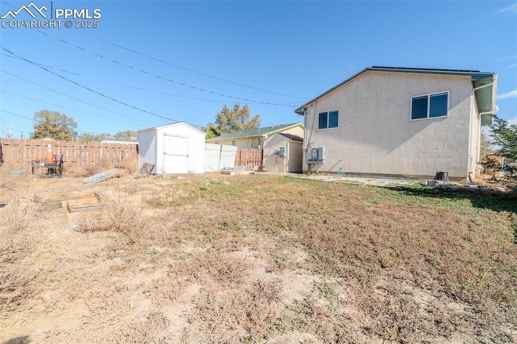 Back of property featuring a storage shed and stucco siding