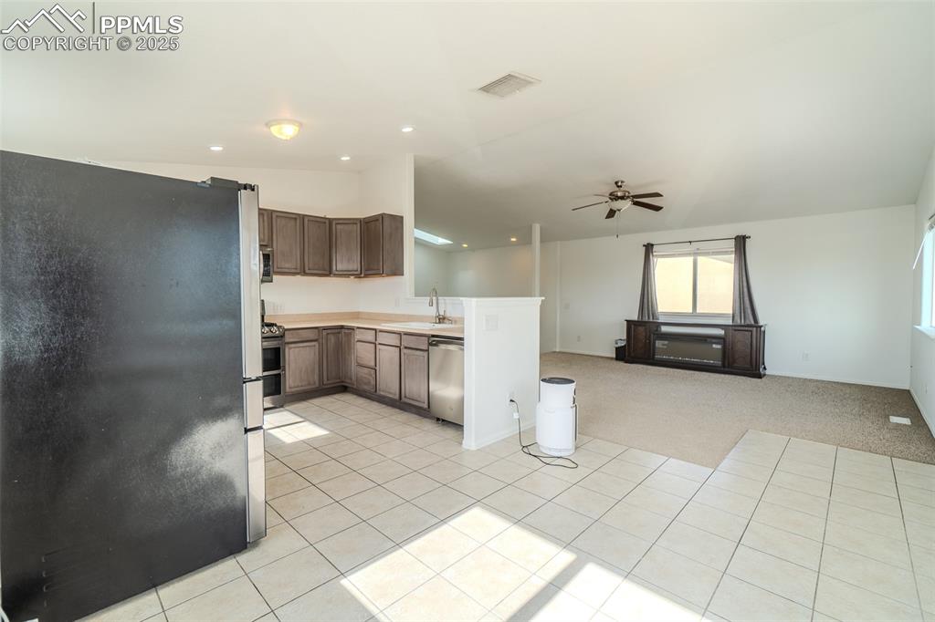 Kitchen featuring appliances with stainless steel finishes, vaulted ceiling, light countertops, open floor plan, and a ceiling fan
