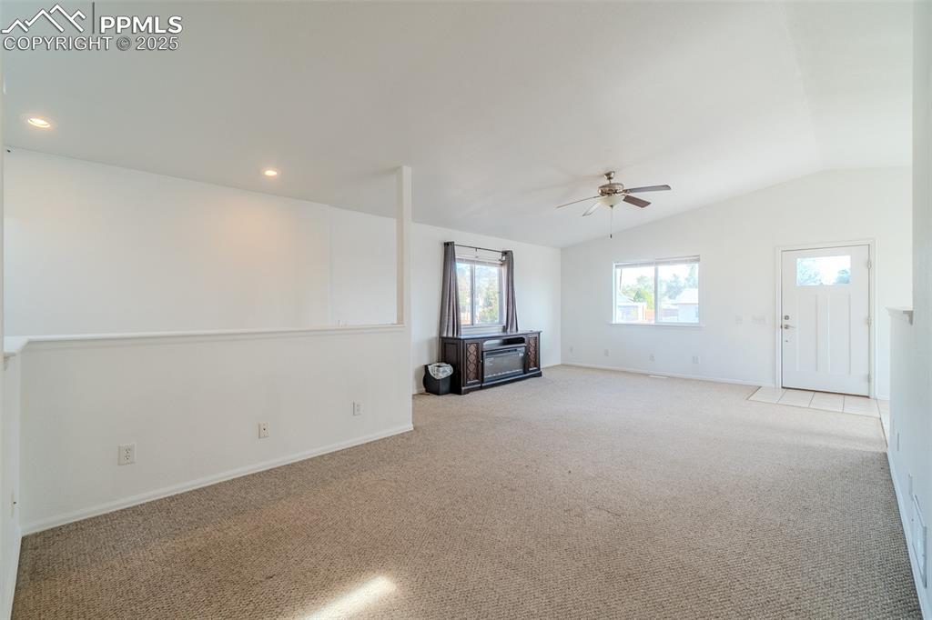 Unfurnished living room with carpet floors, vaulted ceiling, ceiling fan, and recessed lighting