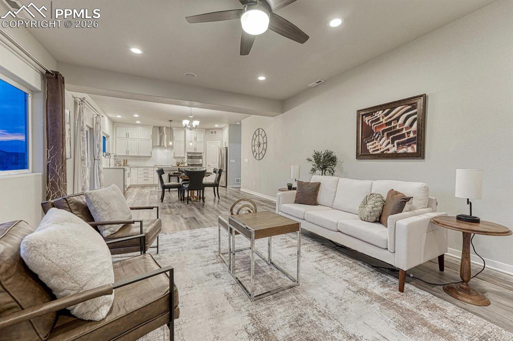 Living room with ceiling fan, light wood-type flooring, and recessed lighting