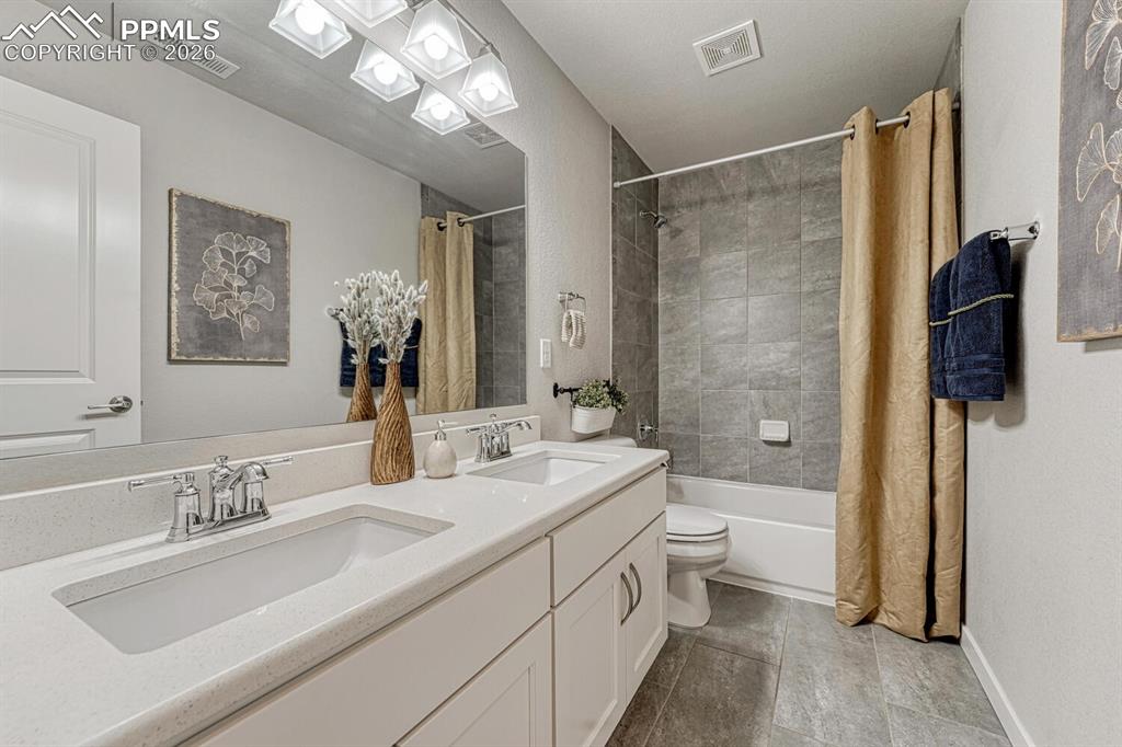 Full bath featuring double vanity and shower / bath combination with curtain