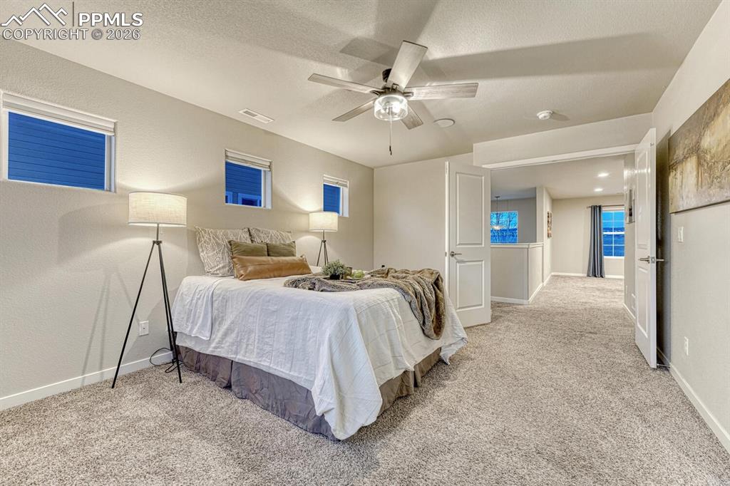 Bedroom with ceiling fan, light colored carpet, and a textured ceiling