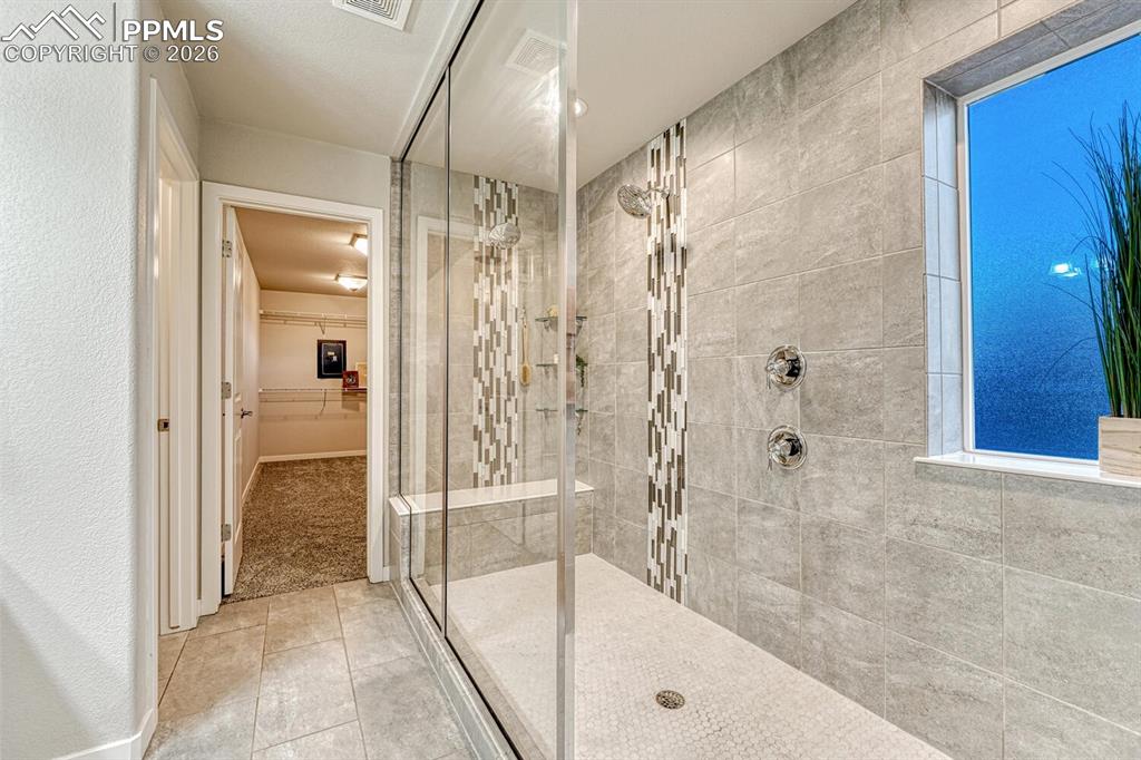 Full bath with a walk in closet, a walk in shower, and light tile patterned flooring
