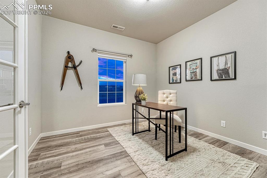 Professional office area with French doors and elegant light-finished floors.