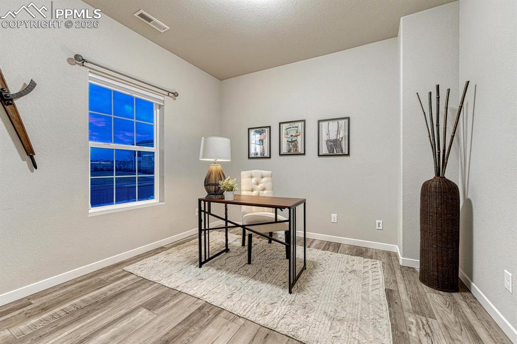 Office area with light wood-style floors and a textured ceiling