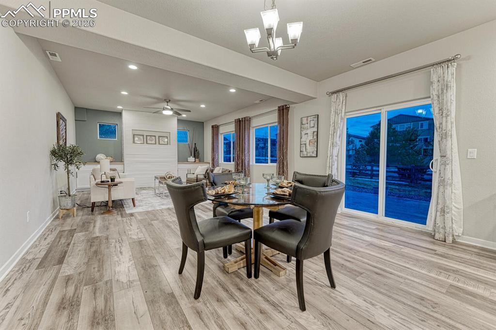 Elegant dining room illuminated by a chandelier and adorned with light luxury vinyl flooring.