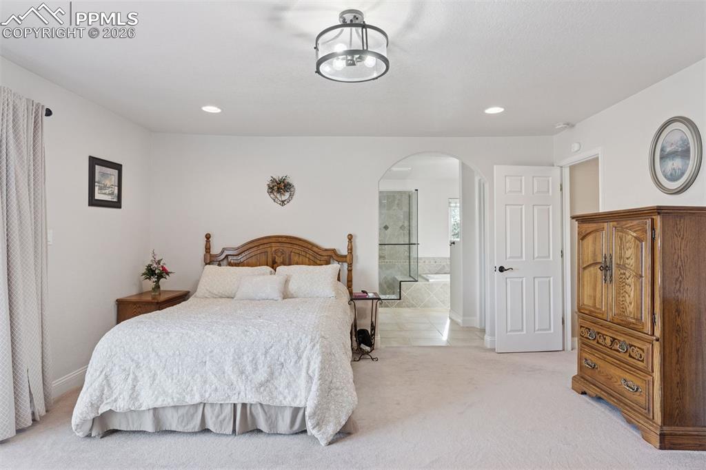 Primary suite featuring light colored carpet, ensuite bath,  and recessed lighting