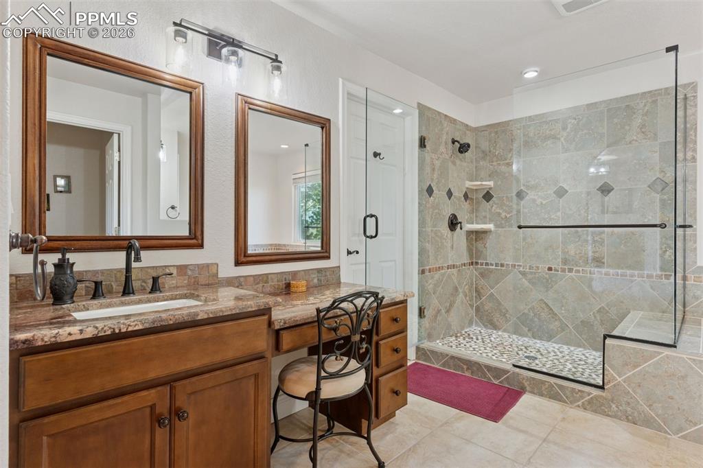 Full bathroom with heated floor, multiple vanities, a stall shower w/bench