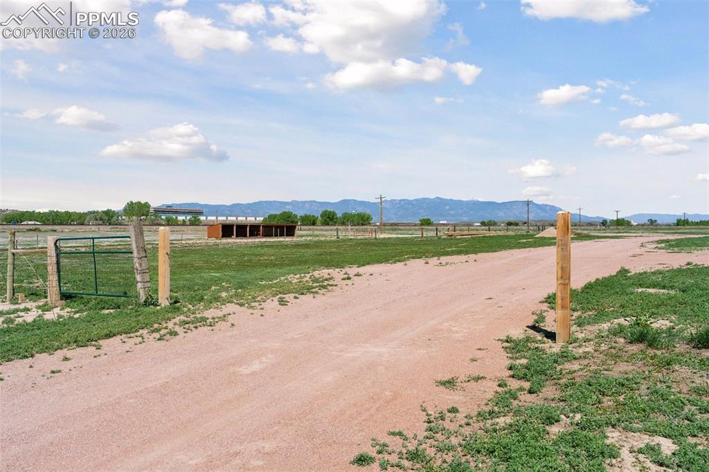 View of dirt / gravel road featuring a view of rural / pastoral area and a mountain view