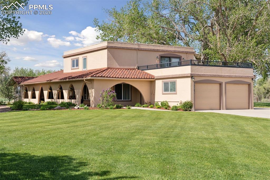 View of front of home featuring stucco siding, an attached garage, a front lawn, and driveway