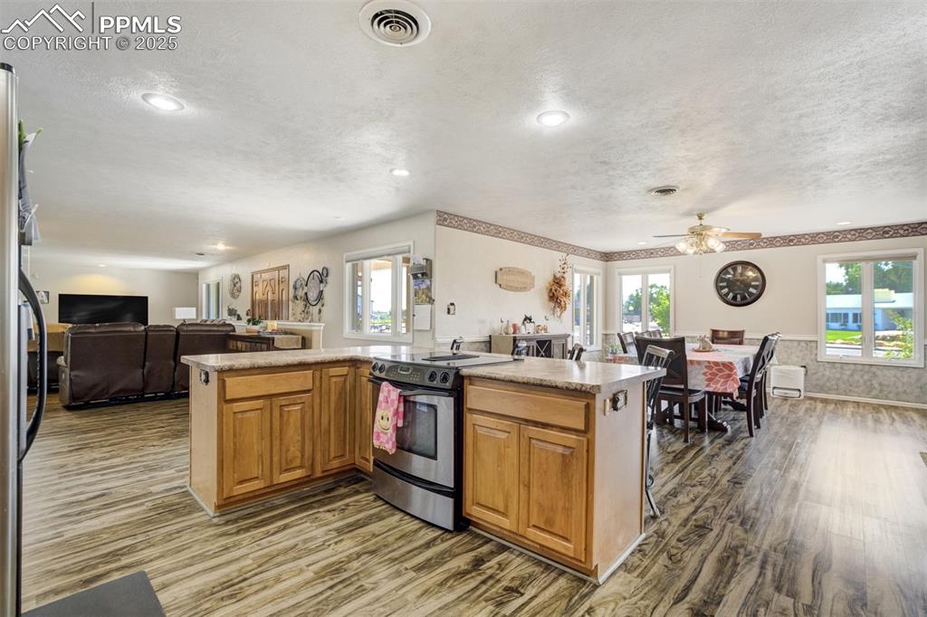 Kitchen featuring open floor plan, brown cabinets, stainless steel appliances, healthy amount of natural light, and a textured ceiling