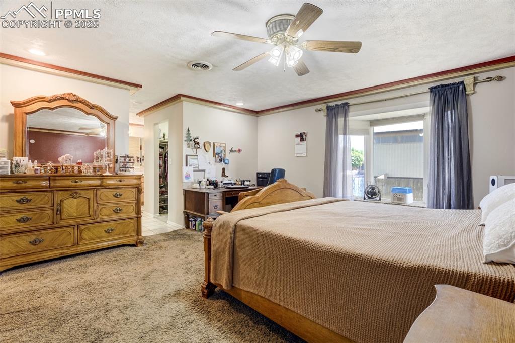 Primary Bedroom with light colored carpet, ceiling fan, a textured ceiling, 