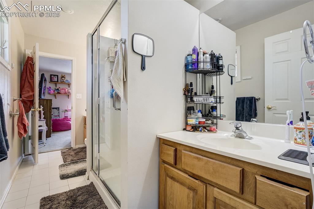 Bathroom attached to both bedrooms,  shower stall,  2 vanities, and light tile patterned flooring