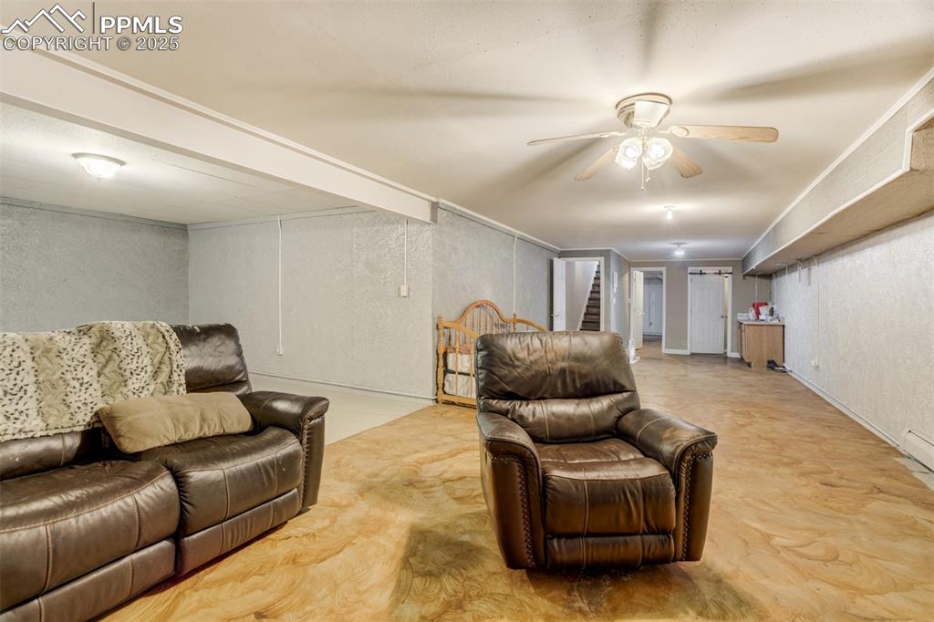 Living room featuring stairs, a textured wall, and ceiling fan