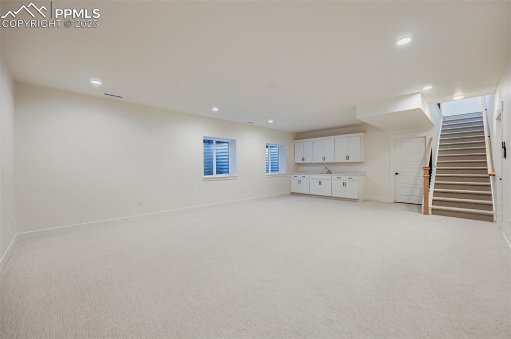 Basement featuring stairs, light colored carpet, and recessed lighting