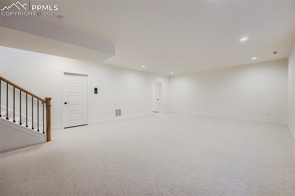 Empty room with stairs, light colored carpet, and recessed lighting