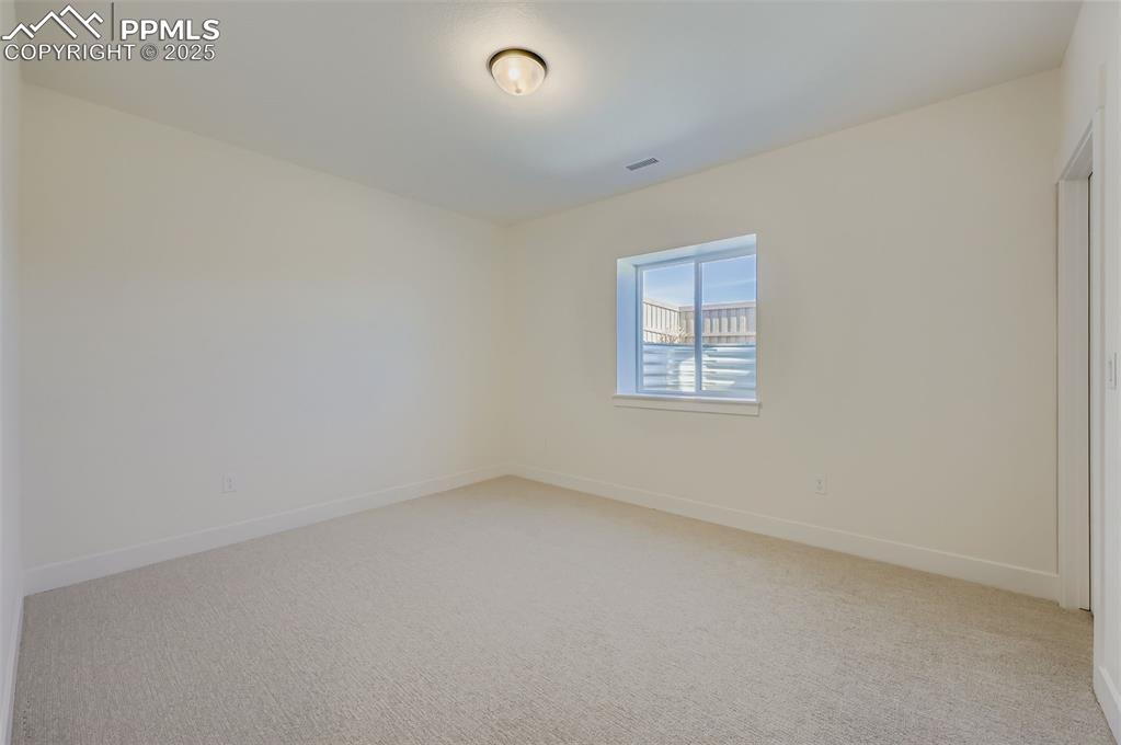 Empty room featuring light colored carpet and baseboards