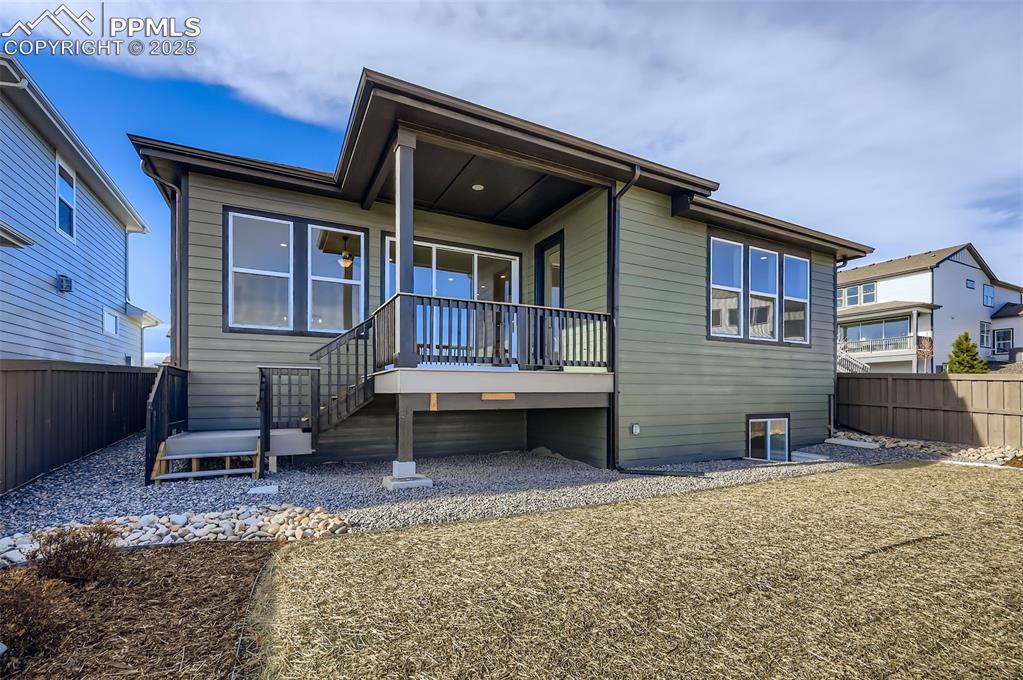 Rear view of house featuring a fenced backyard, a wooden deck, and stairway