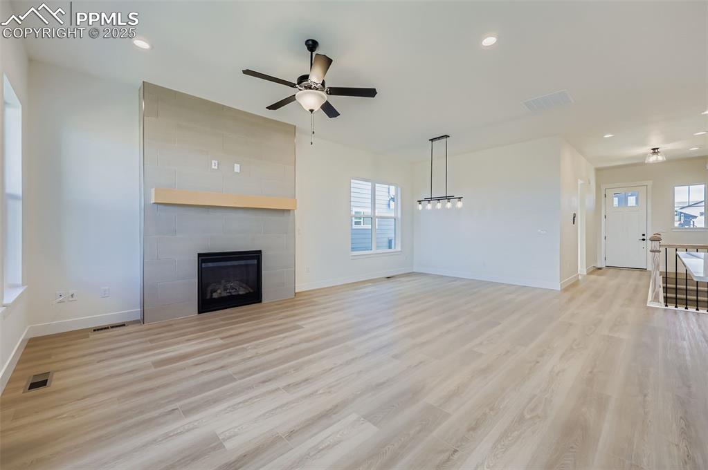 Unfurnished living room featuring a tile fireplace, light wood-style floors, recessed lighting, and a ceiling fan