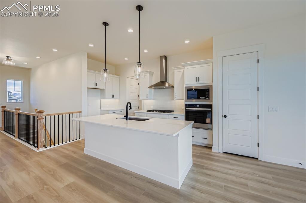 Kitchen with white cabinetry, a kitchen island with sink, appliances with stainless steel finishes, light wood-style floors, and recessed lighting