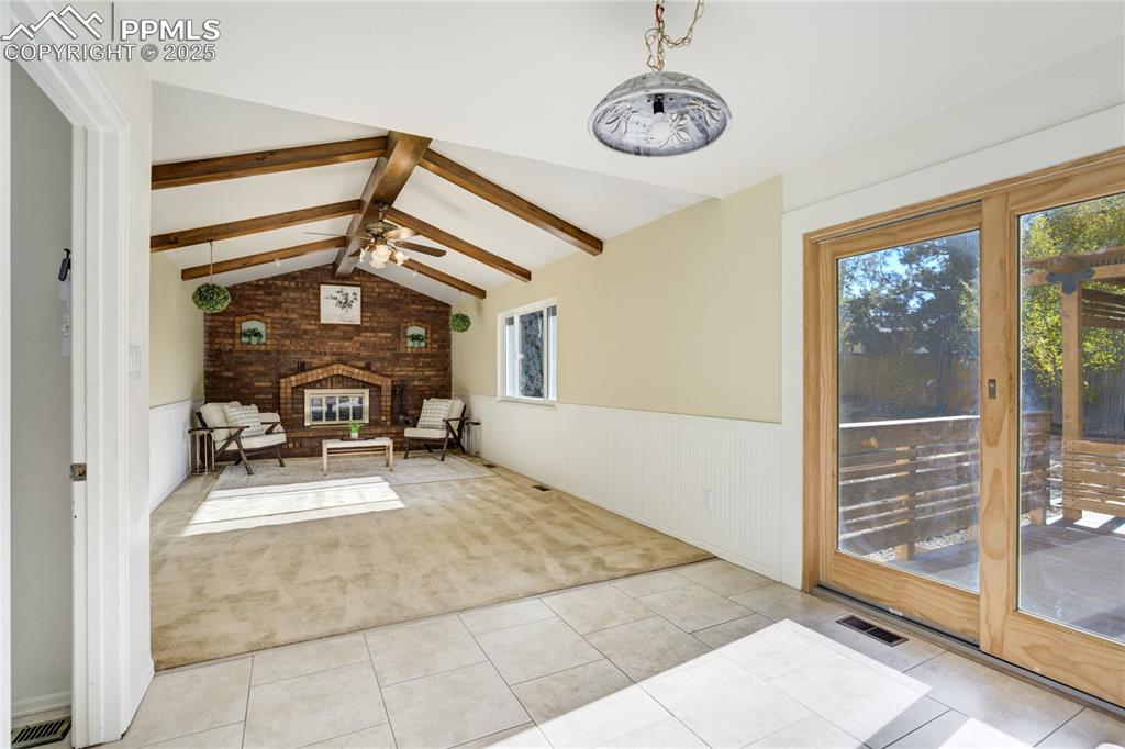 Den with wood beam vaulted ceiling and grand fireplace