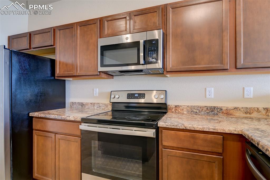 Kitchen featuring appliances with stainless steel finishes and brown cabinets