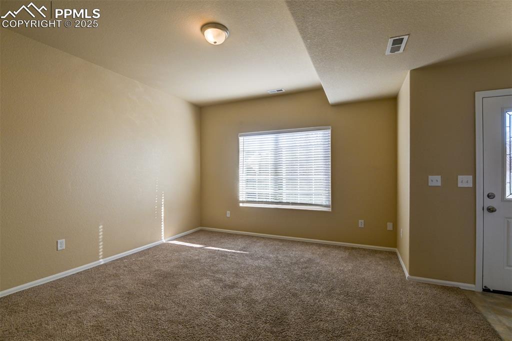 Carpeted spare room featuring baseboards and a textured ceiling