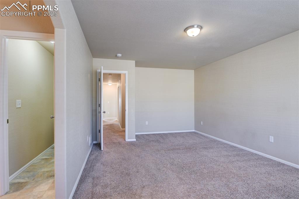 Unfurnished bedroom with baseboards and light colored carpet