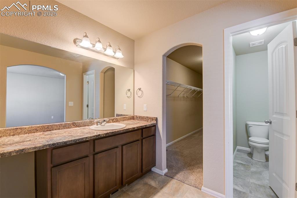 Full bathroom featuring vanity and a walk in closet