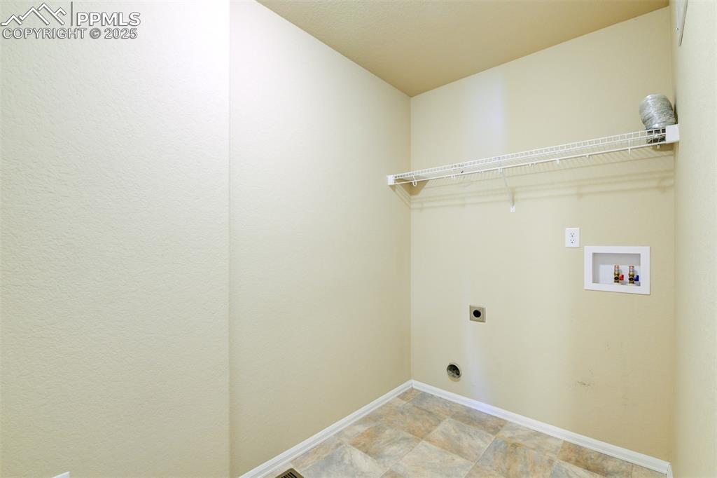 Laundry room with hookup for an electric dryer, washer hookup, and stone finish flooring