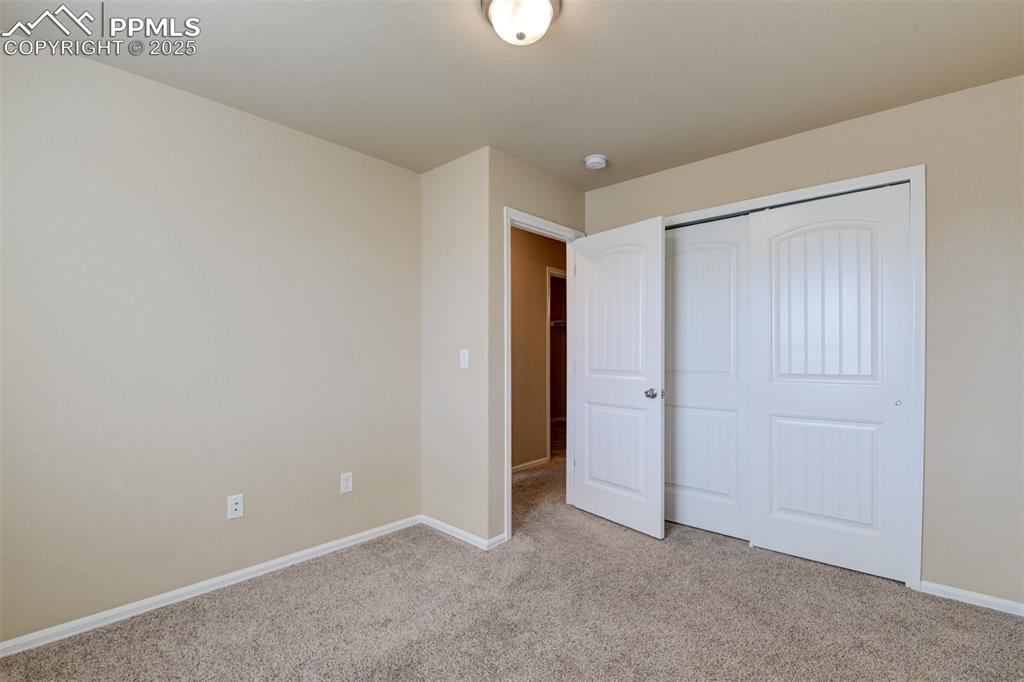 Unfurnished bedroom featuring light carpet and a closet