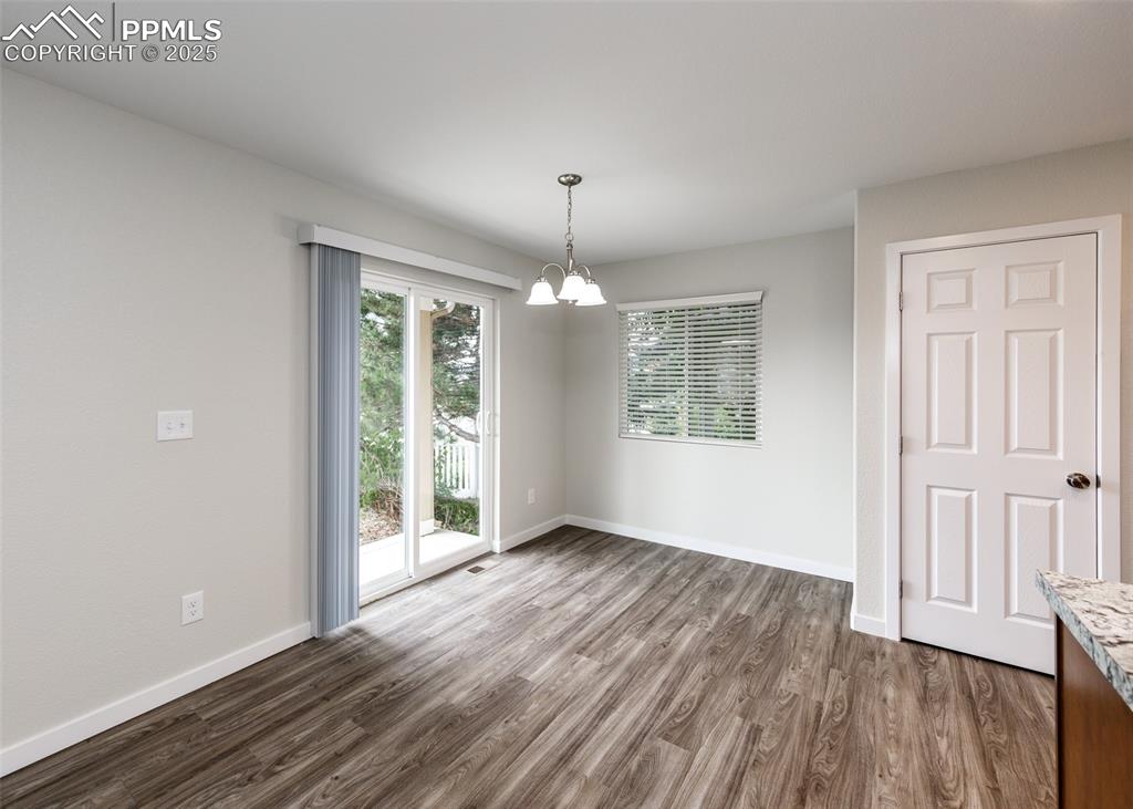 Unfurnished dining area featuring dark wood-style flooring and a chandelier