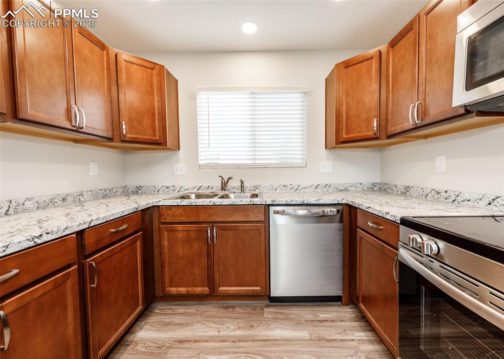 Kitchen featuring stainless steel appliances, brown cabinets, light wood-type flooring, and recessed lighting