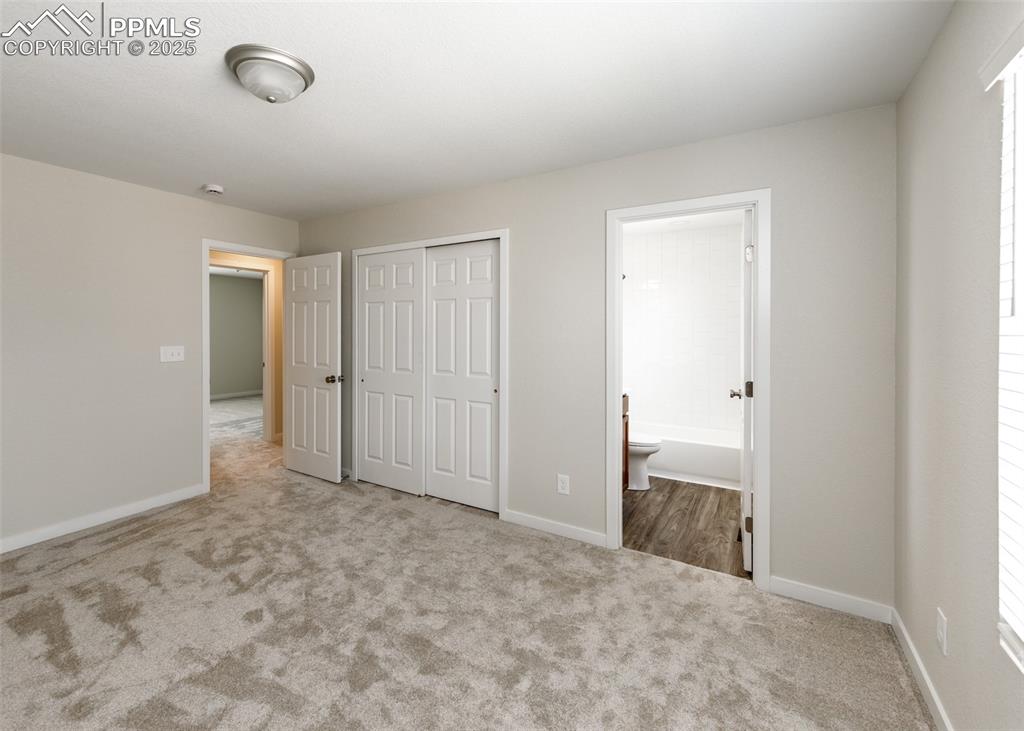 Unfurnished bedroom featuring carpet, a closet, and ensuite bathroom