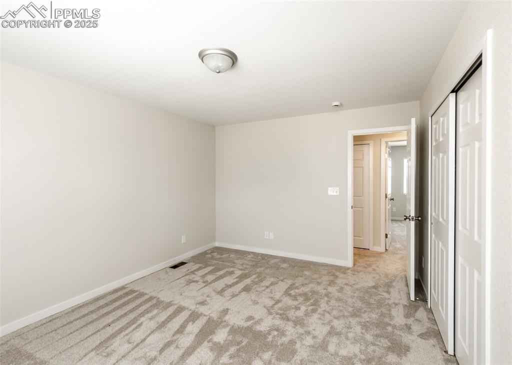 Unfurnished bedroom with light carpet and a closet